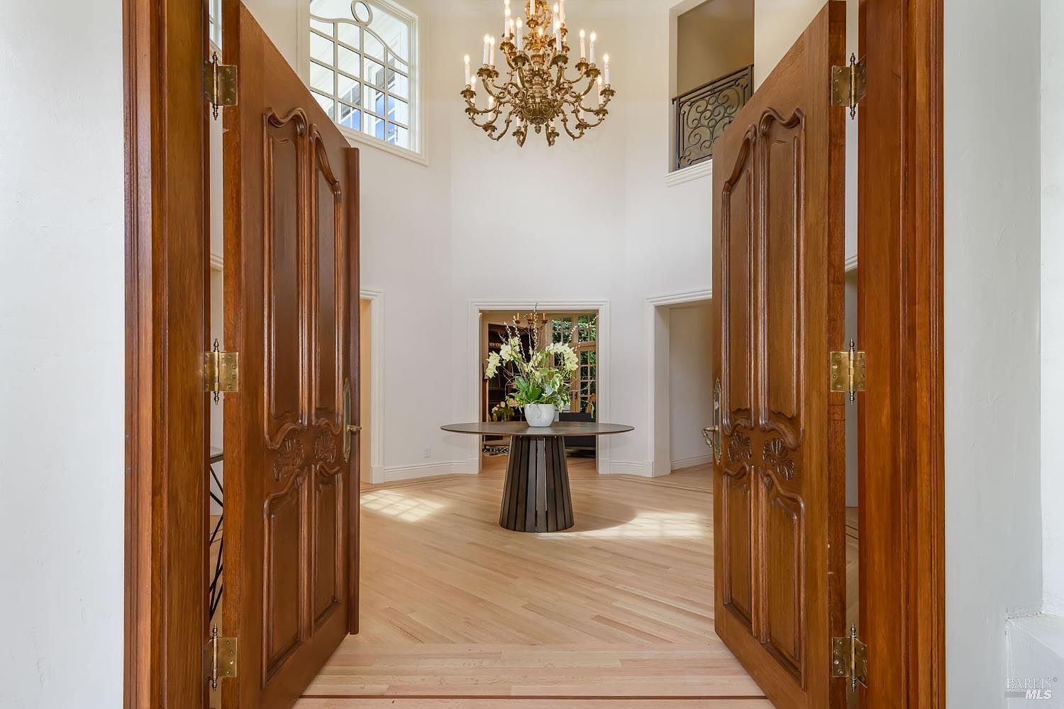 Double-height foyer with French doors and chandelier